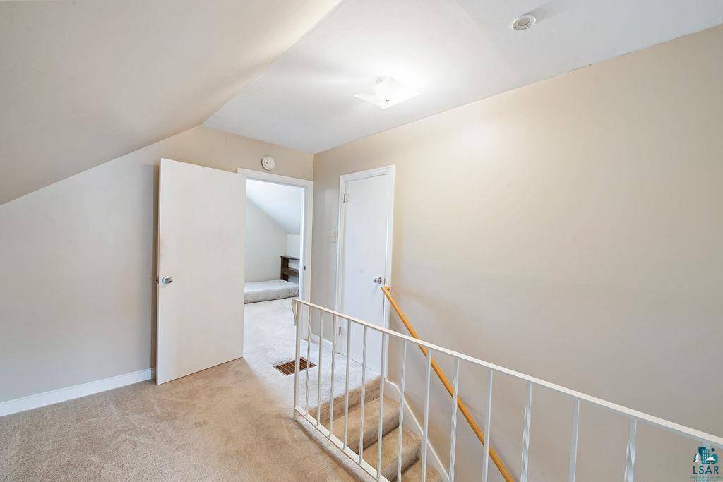 122 3rd Street Cloquet, MN 55720 - Photo 12 of 42 Carpeted upper level with sloped ceilings, white painted walls, and an open doorway leading to an additional space