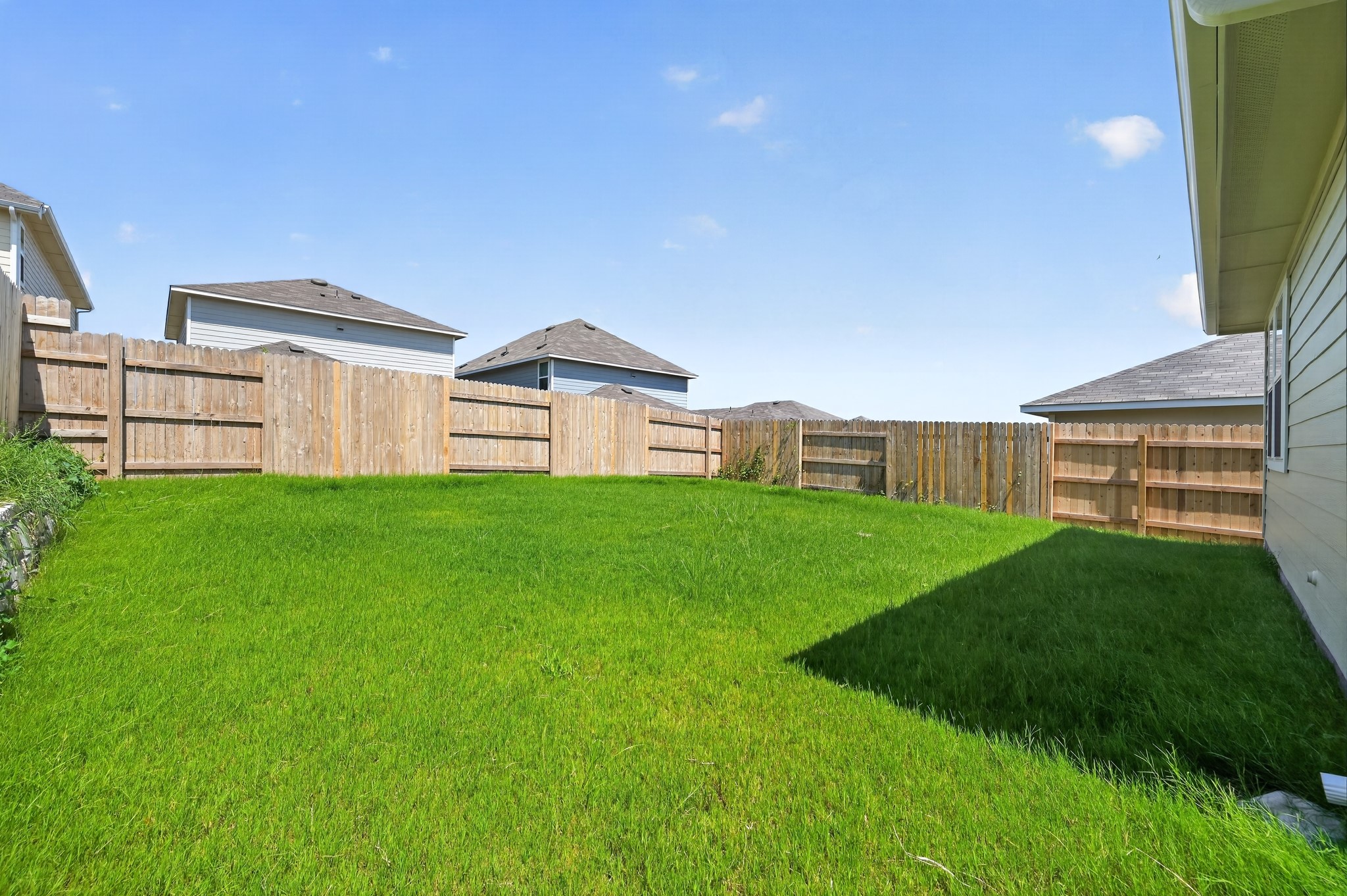 2704 Towy Road Manor, TX 78653 - Photo 25 of 36 An enclosed grassy lawn stands ready for outdoor recreation beneath clear blue skies.
