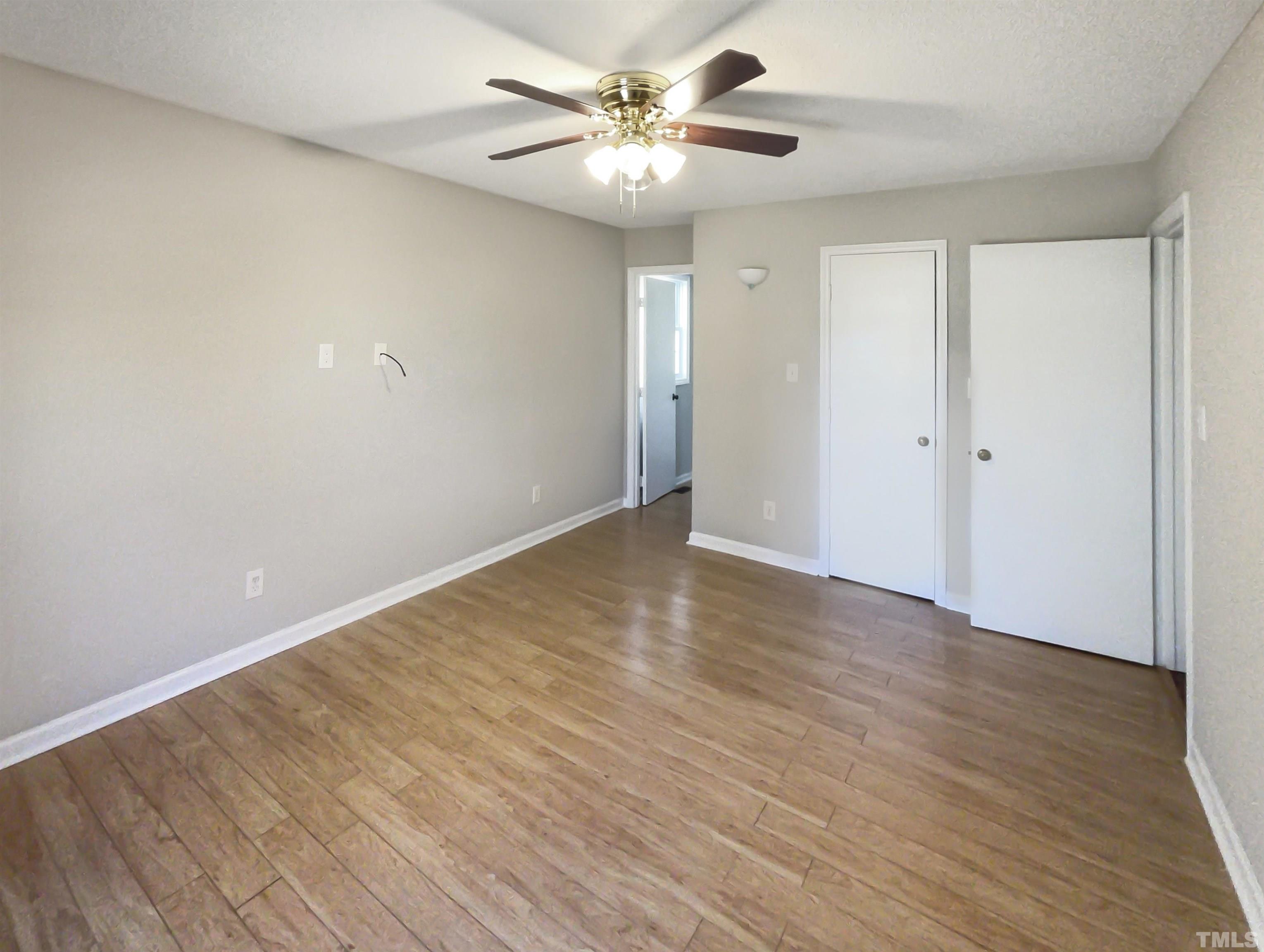 8889 Mt Pleasant Church Road Willow Spring, NC 27592 - Photo 16 of 18 a view of an empty room with chandelier fan and wooden floor
