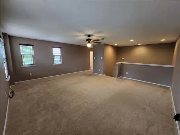 an empty room with a ceiling fan and window