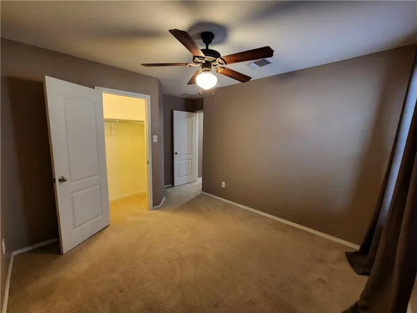 an empty room with a ceiling fan and a window