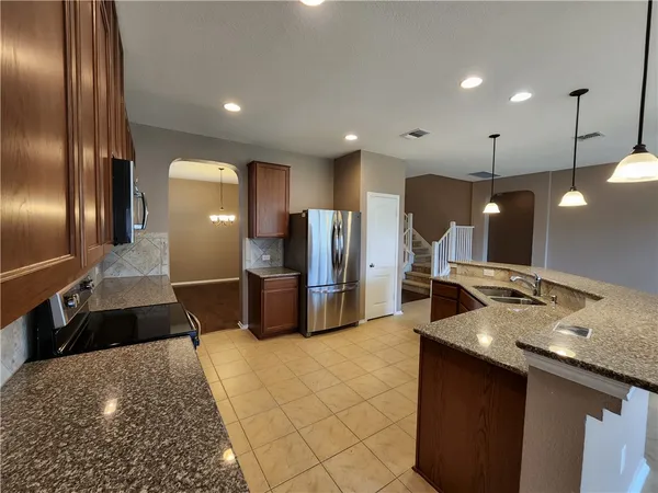 a large kitchen with a large counter top stainless steel appliances and cabinets
