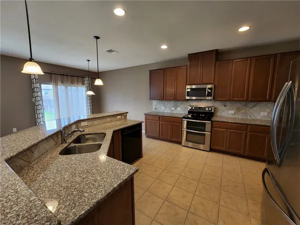 a kitchen with kitchen island granite countertop a sink appliances and cabinets