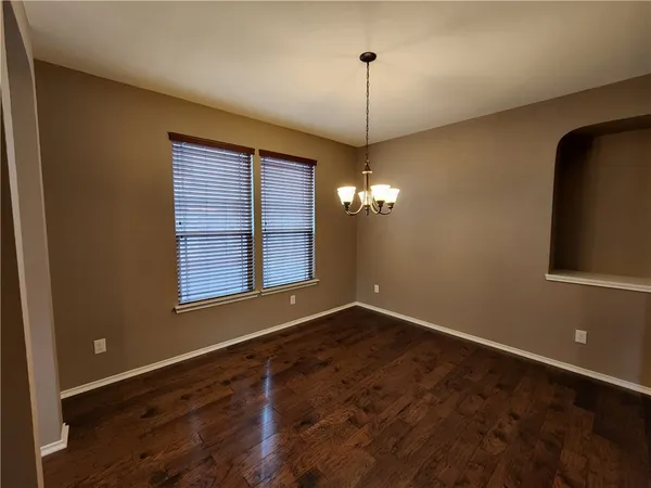 a view of an empty room with window and chandelier fan