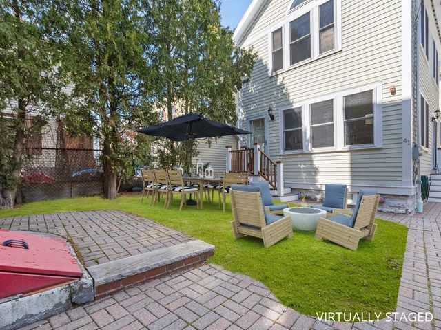a view of a backyard with couches table and chairs under an umbrella