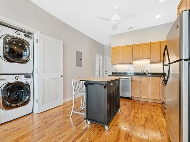 a kitchen with granite countertop a sink cabinets stainless steel appliances and a window