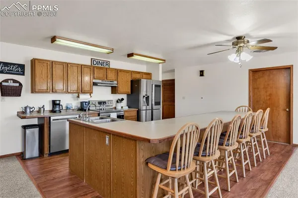 a kitchen with stainless steel appliances a stove a sink dishwasher a refrigerator with a dining table and chairs