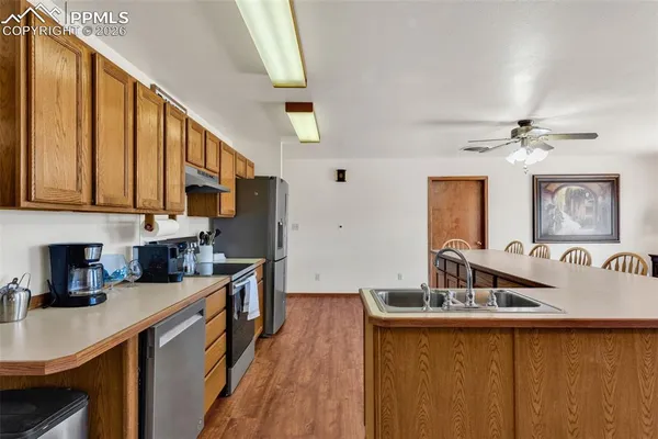 a kitchen with stainless steel appliances a sink a stove a refrigerator cabinets and a window