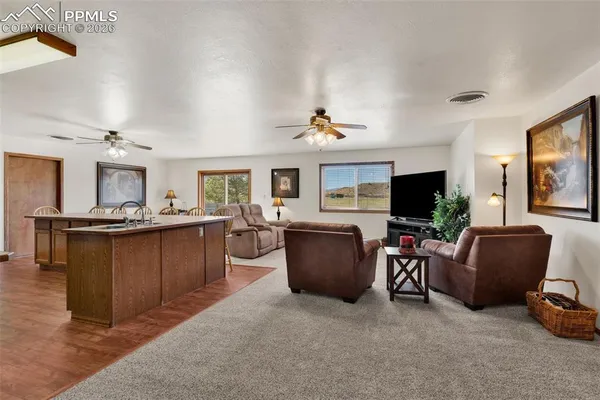 a living room with furniture a flat screen tv and kitchen view