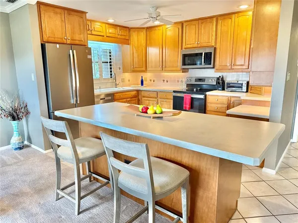 a kitchen with stainless steel appliances granite countertop a refrigerator a stove top oven a sink a dining table and chairs with wooden floor