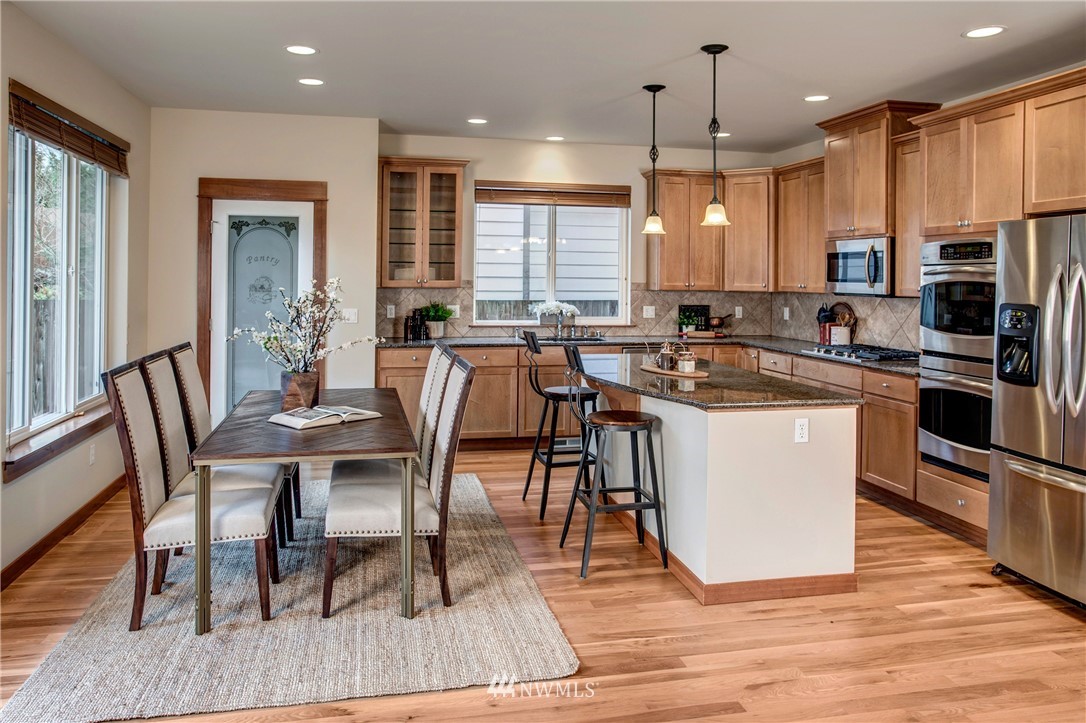 3811 222nd Place Southeast Bothell, WA 98021 - Photo 8 of 35 a kitchen with stainless steel appliances granite countertop a stove top oven a sink dishwasher a dining table and chairs with wooden floor