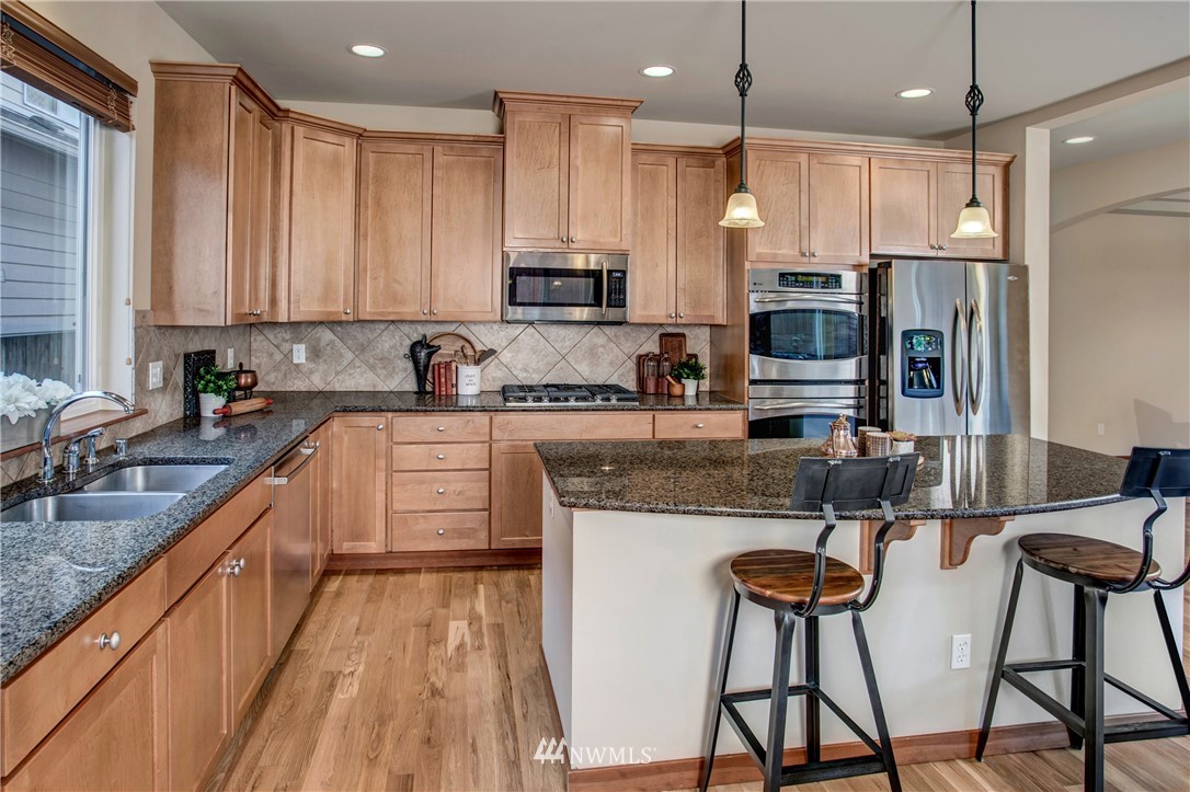 3811 222nd Place Southeast Bothell, WA 98021 - Photo 10 of 35 a kitchen with stainless steel appliances kitchen island granite countertop a sink refrigerator and cabinets