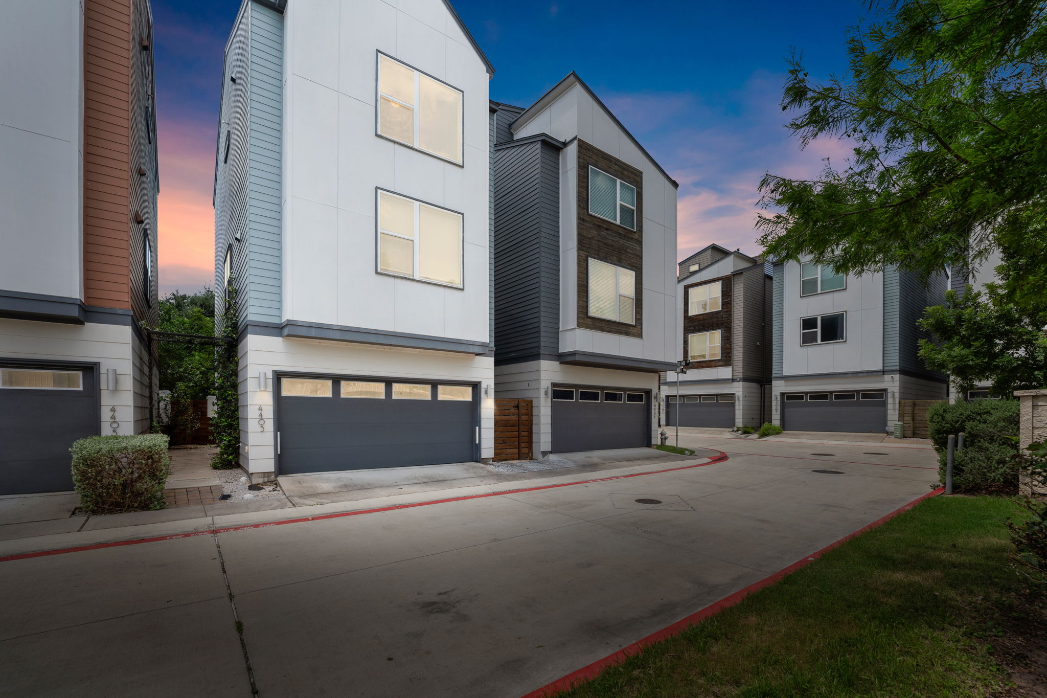 4403 Swift Path Austin, TX 78741 - Photo 3 of 32 Modern townhome architecture featuring a white and gray facade, multiple windows, and a dark gray garage door