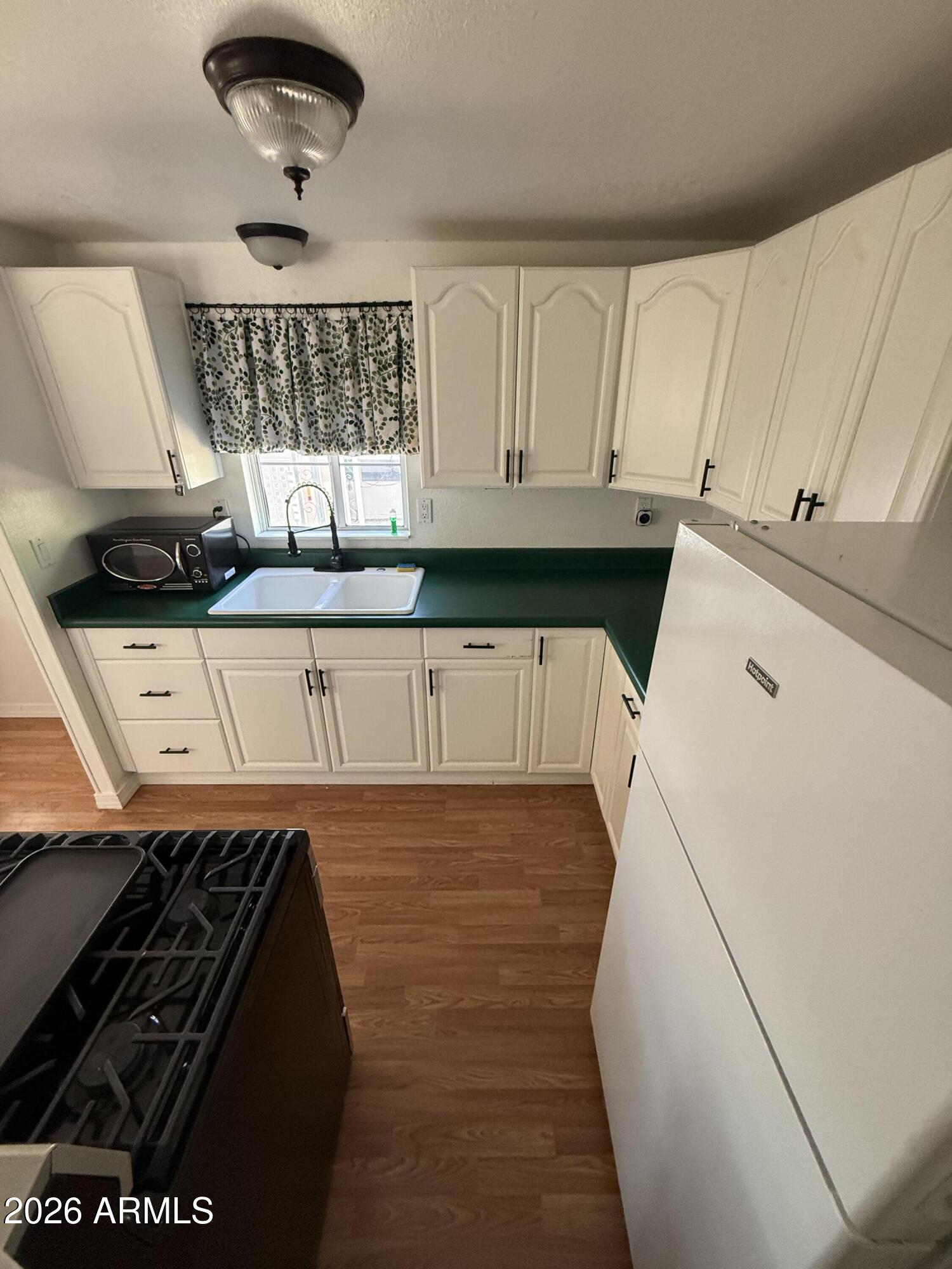 9501 East Broadway Road, Unit 48 Mesa, AZ 85208 - Photo 5 of 12 a kitchen with a stove and white cabinets