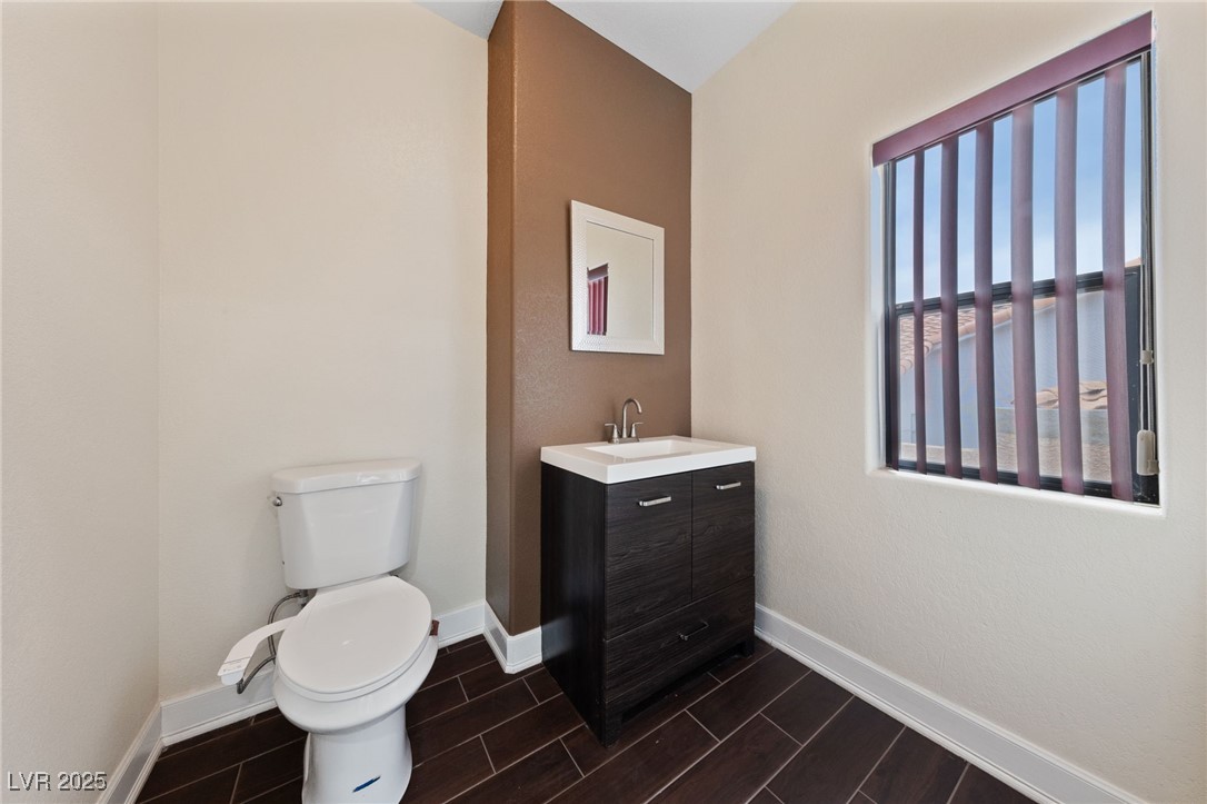 1056 Calico Ridge Drive Henderson, NV 89011 - Photo 33 of 67 Half bath with toilet, baseboards, wood finish floors, and vanity
