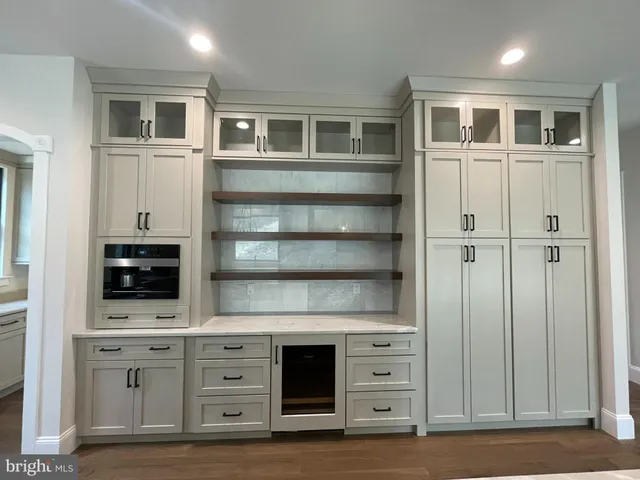 a large kitchen with a large center island wooden floor stainless steel appliances and cabinets