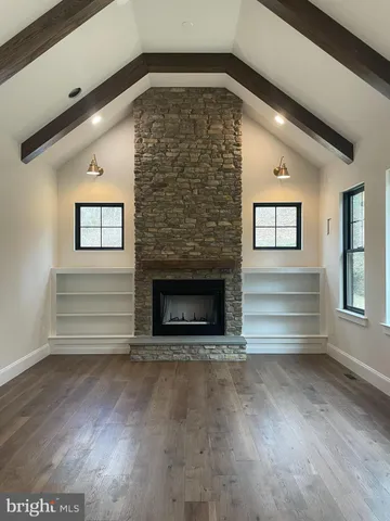 an empty room with wooden floor fireplace and windows