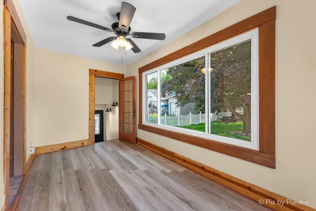 a view of n empty room with wooden floor and a window