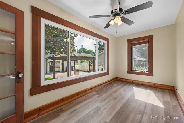 a view of an empty room with window chandelier fan and wooden floor
