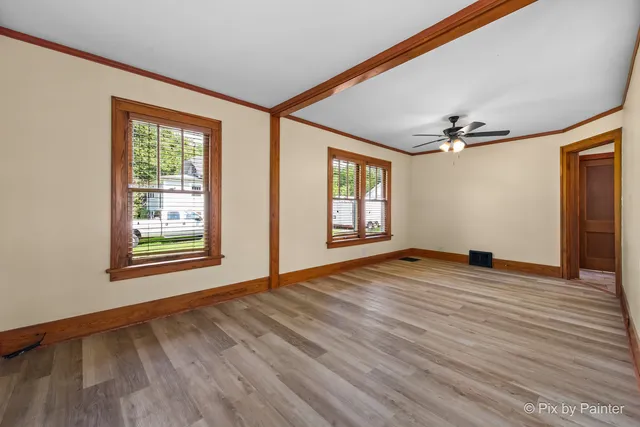 a view of empty room with wooden floor and fan