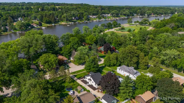 an aerial view of ocean with residential house with outdoor space and trees all around