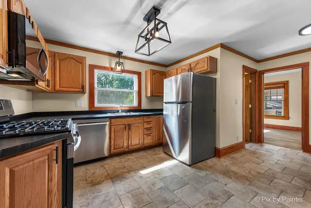 a kitchen with stainless steel appliances granite countertop a refrigerator a stove a sink and a microwave