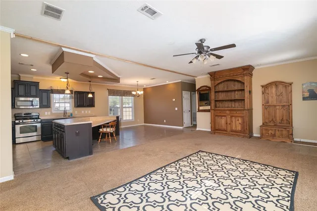 a large living room with stainless steel appliances kitchen island granite countertop furniture and a fireplace