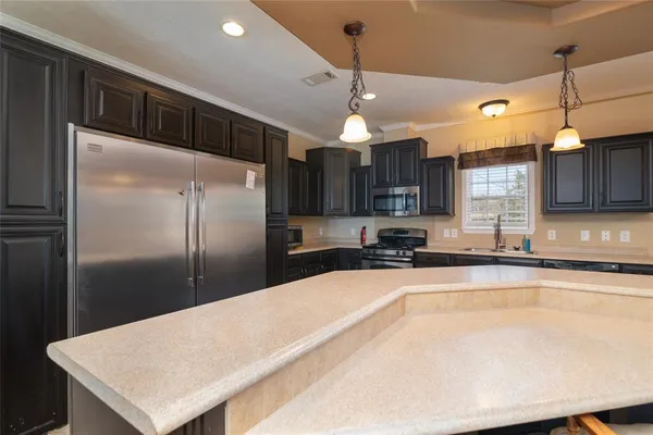 a kitchen with stainless steel appliances a sink a refrigerator a center island a stove and cabinets