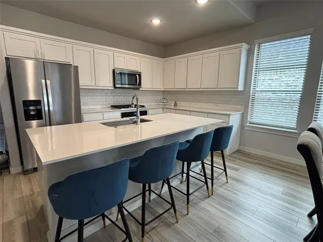 a kitchen with stainless steel appliances a table chairs microwave and refrigerator