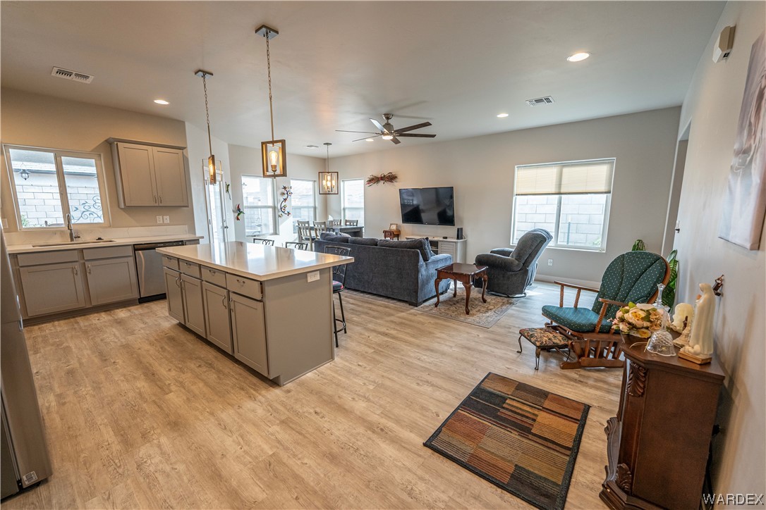 3566 North Kenneth Road Kingman, AZ 86409 - Photo 5 of 35 a large kitchen with kitchen island a stove a sink dishwasher a dining table and chairs with wooden floor