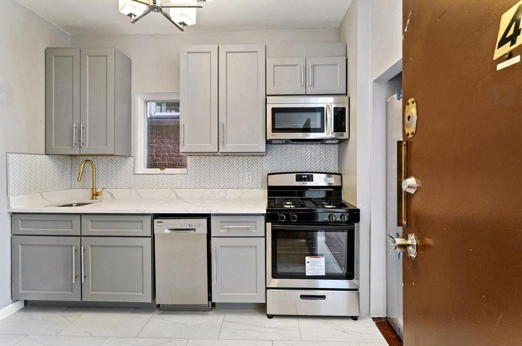 475 Palisade Avenue, Unit 4 Jersey City, NJ 07307 - Photo 4 of 16 a kitchen with white cabinets and stainless steel appliances