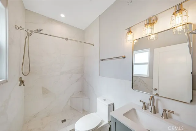 a bathroom with a shower sink vanity mirror and toilet