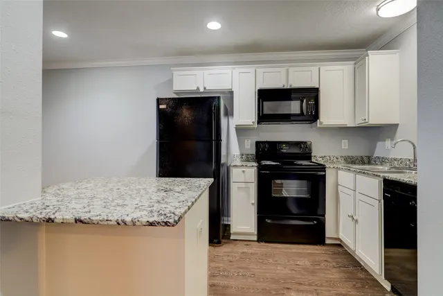 a kitchen with granite countertop a refrigerator and a stove top oven