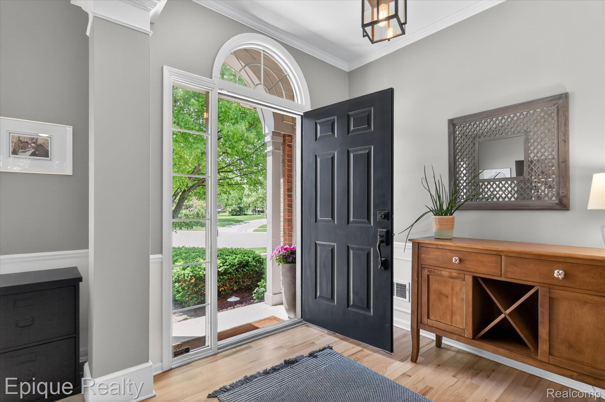 760 Caribou Court Rochester, MI 48307 - Photo 6 of 67 Entryway featuring a paneled black door with transom window and sidelights, crown molding, light wood-finish flooring, and a contemporary ceiling light fixture