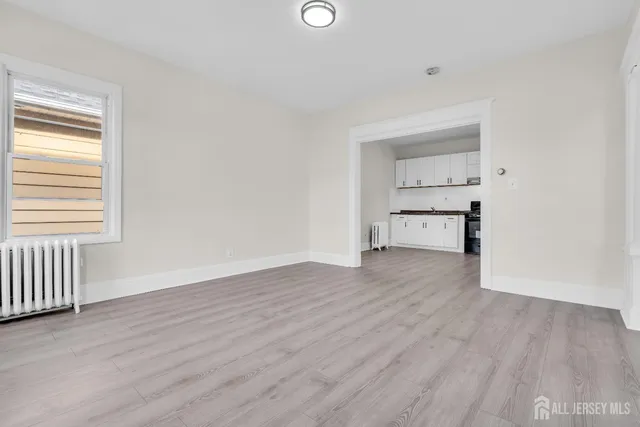 a view of empty room with wooden floor and windows
