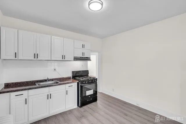 a kitchen with granite countertop white cabinets and stove