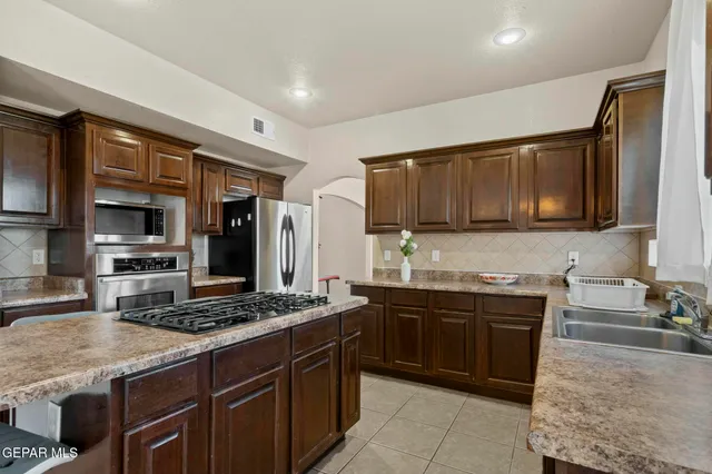 a kitchen with granite countertop a refrigerator stove and sink