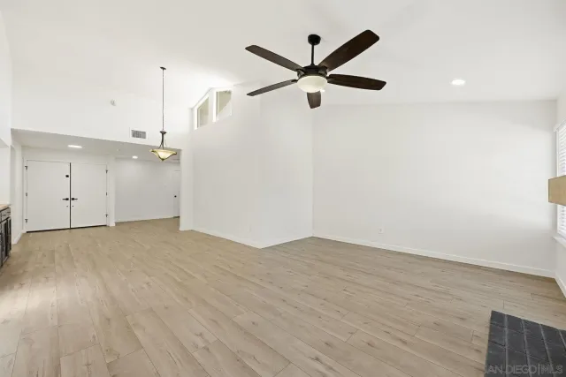 an empty room with wooden floor and a ceiling fan