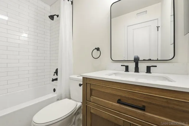 a bathroom with a granite countertop toilet sink and mirror