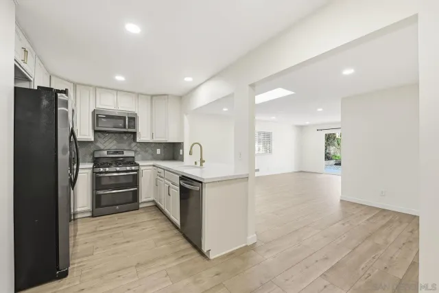 a kitchen with stainless steel appliances granite countertop a refrigerator stove top oven and sink