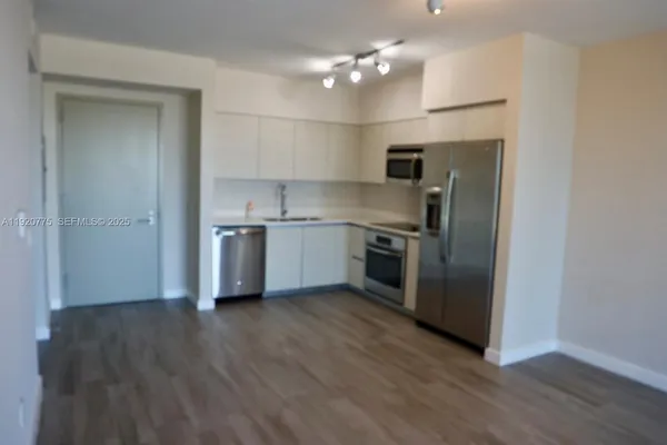 a view of a livingroom with wooden floor and kitchen