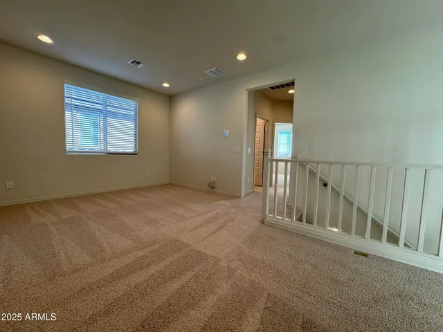 a view of an empty room with wooden floor and windows