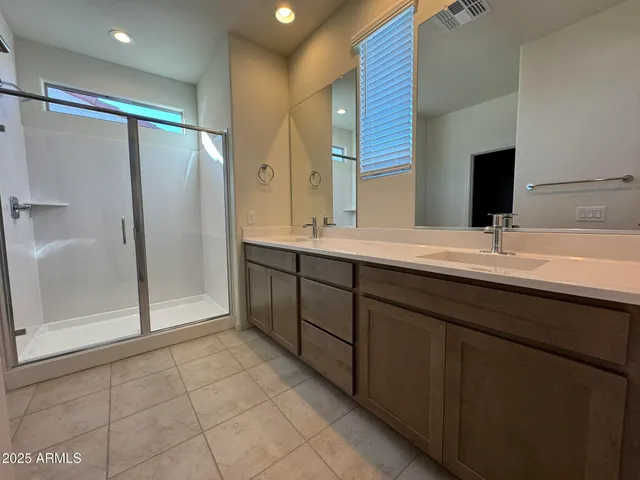 a bathroom with a double vanity sink mirror and shower