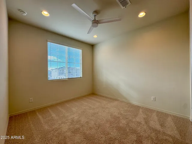 an empty room with a ceiling fan and windows
