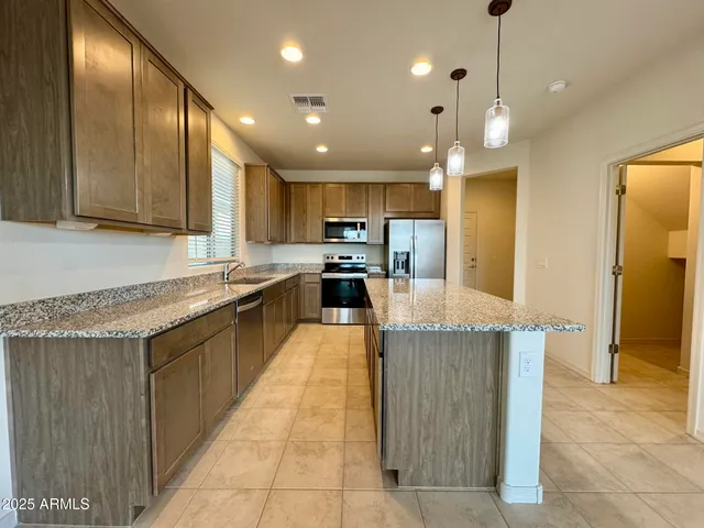 a large kitchen with stainless steel appliances kitchen island granite countertop a large counter top and wooden cabinets