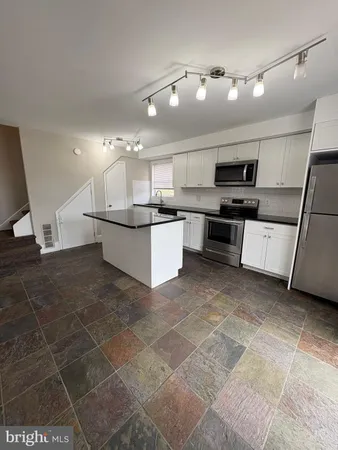 a large kitchen with kitchen island a sink a stove a microwave and a counter top space