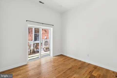 an empty room with wooden floor and a window