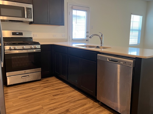 379 Geode Glen Maxwell, TX 78656 - Photo 5 of 12 Kitchen with stainless steel appliances, a peninsula, a sink, light countertops, and light wood-type flooring