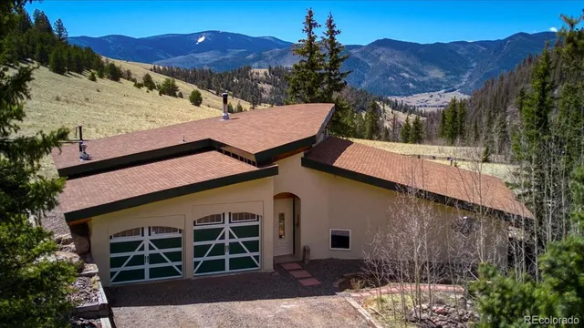 a front view of a house with a yard and mountain view
