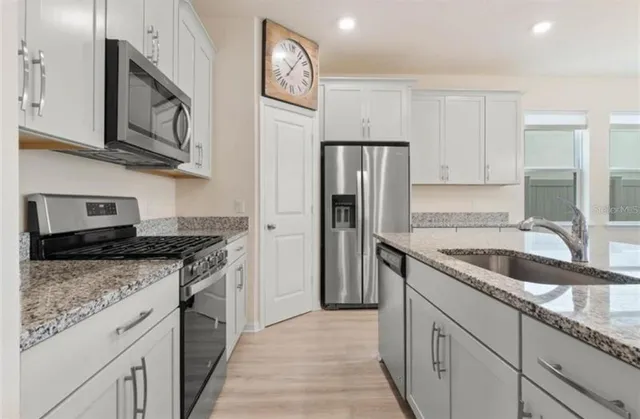 a kitchen with stainless steel appliances granite countertop a sink stove and refrigerator